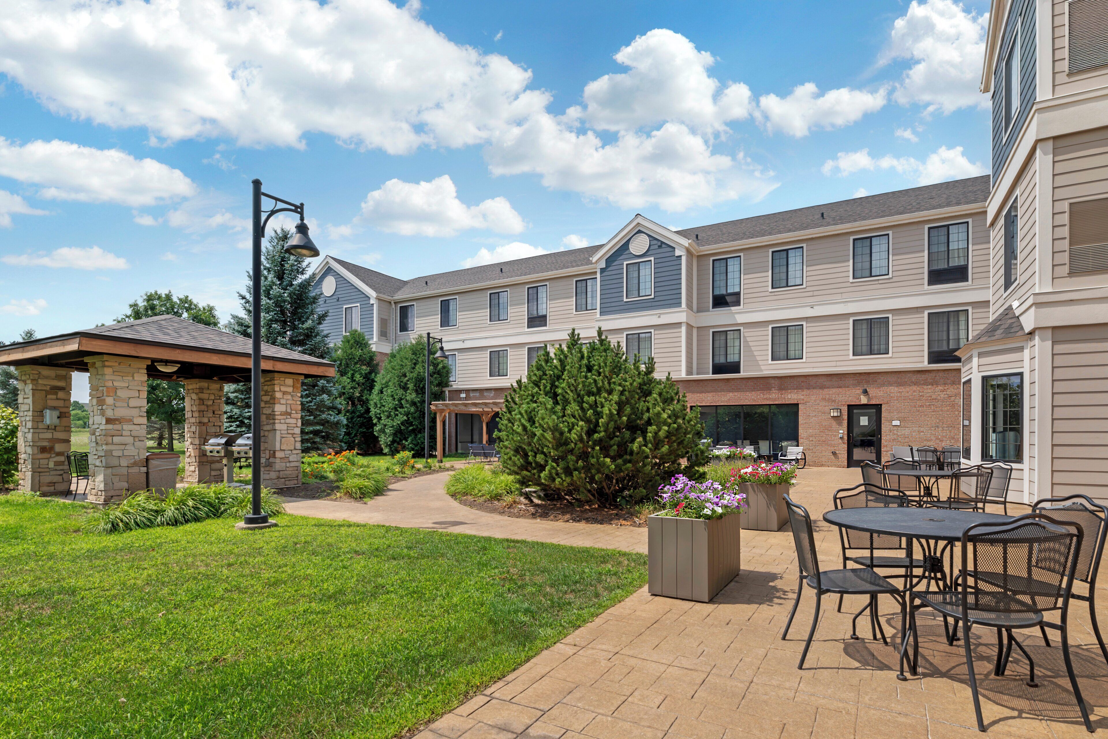 A courtyard with a gazebo, outdoor seating, and a brick building with multiple windows.