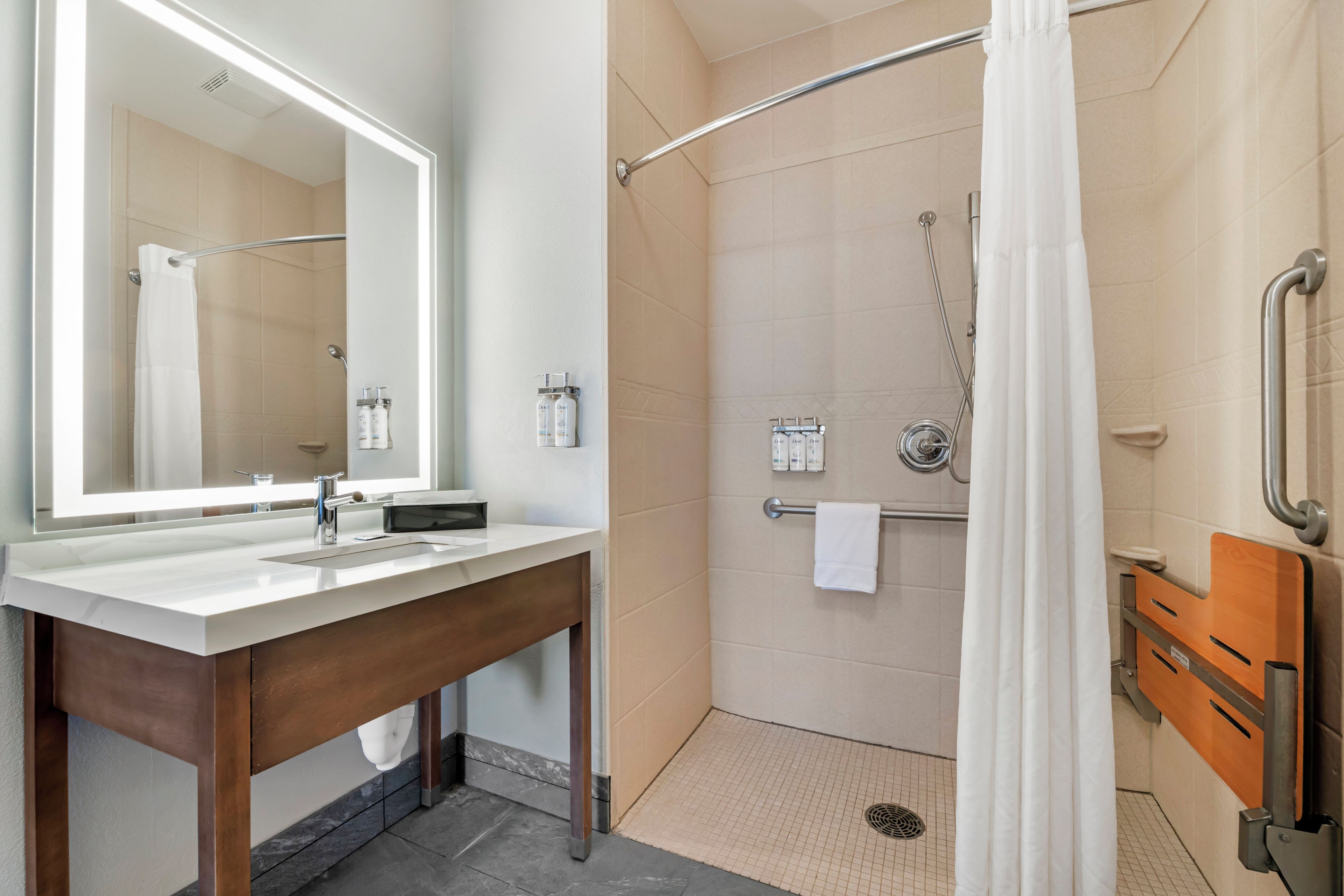 A modern bathroom with a large mirror, a sink, and a shower area.