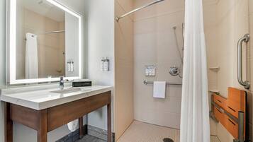 A modern bathroom with a large mirror, a sink, and a shower area.
