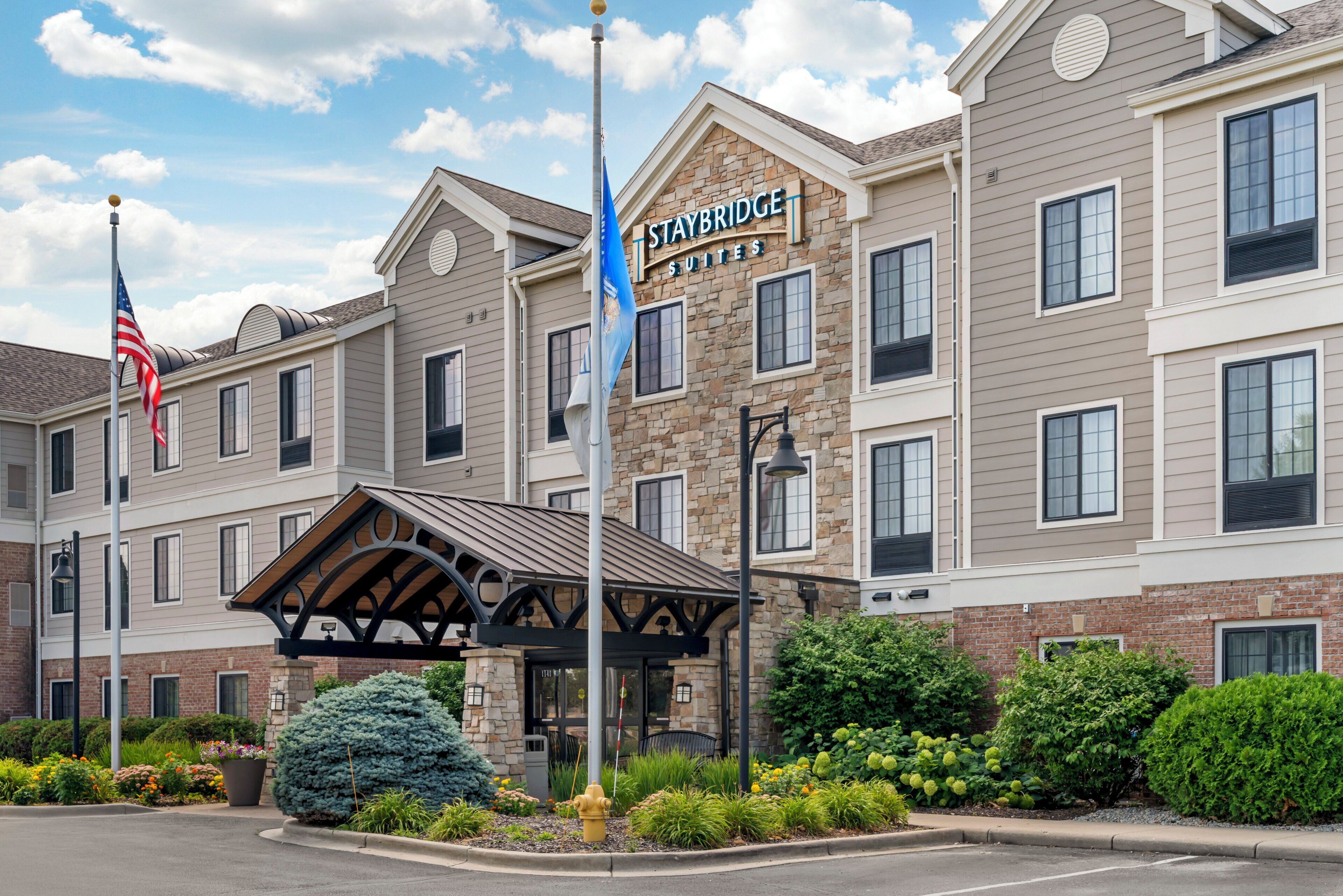 Un hôtel à la façade en pierre, doté de nombreuses fenêtres et d’une enseigne indiquant « STAYBRIDGE SUITES ».