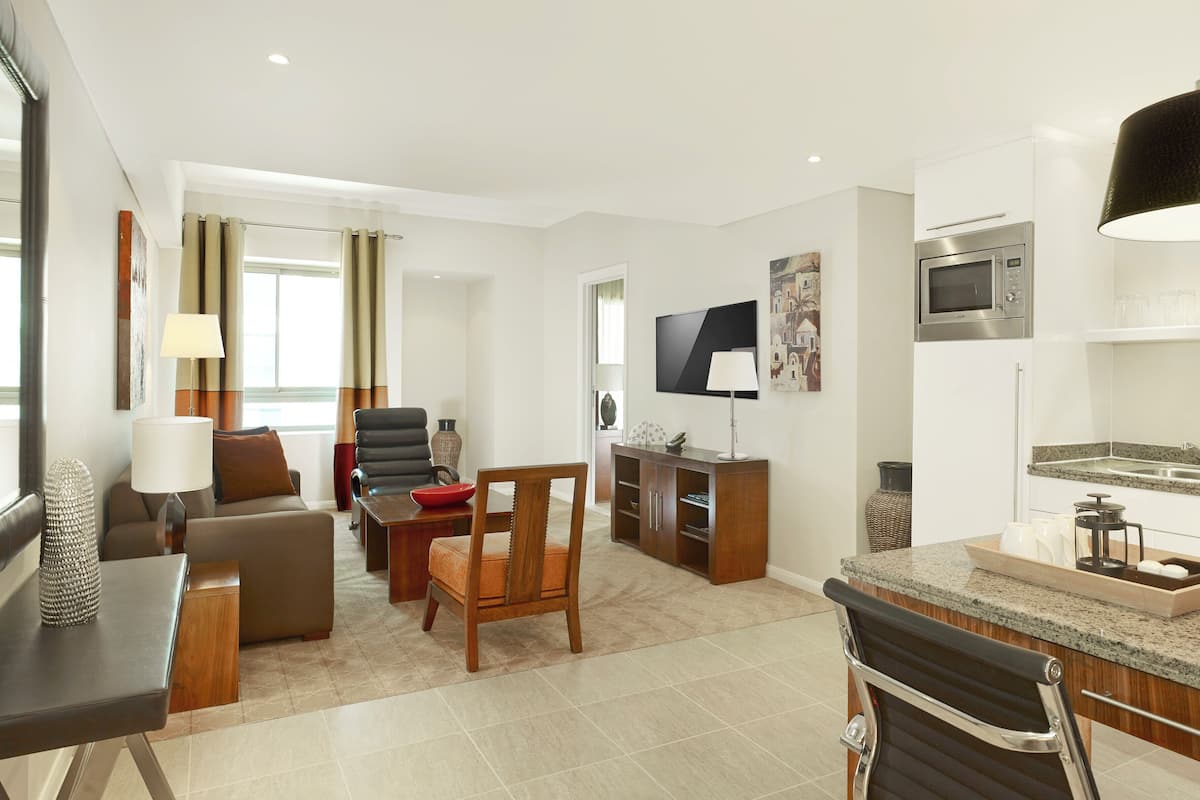 Uma sala de estar moderna com um sofá, cadeiras, uma TV e um espaço de jantar com mesa e cadeiras.