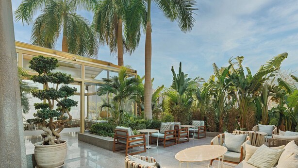 A spacious outdoor lounge area with comfortable seating, a variety of plants, and a glass-enclosed structure. - Staybridge Suites Cairo Citystars by IHG (Cairo)