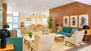 A modern hotel lobby with a seating area, wooden paneling, and artwork on the walls. - Staybridge Suites Cairo Citystars by IHG (Cairo)