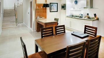 A modern kitchen with white cabinets, a wooden dining table, and a built-in island with seating.