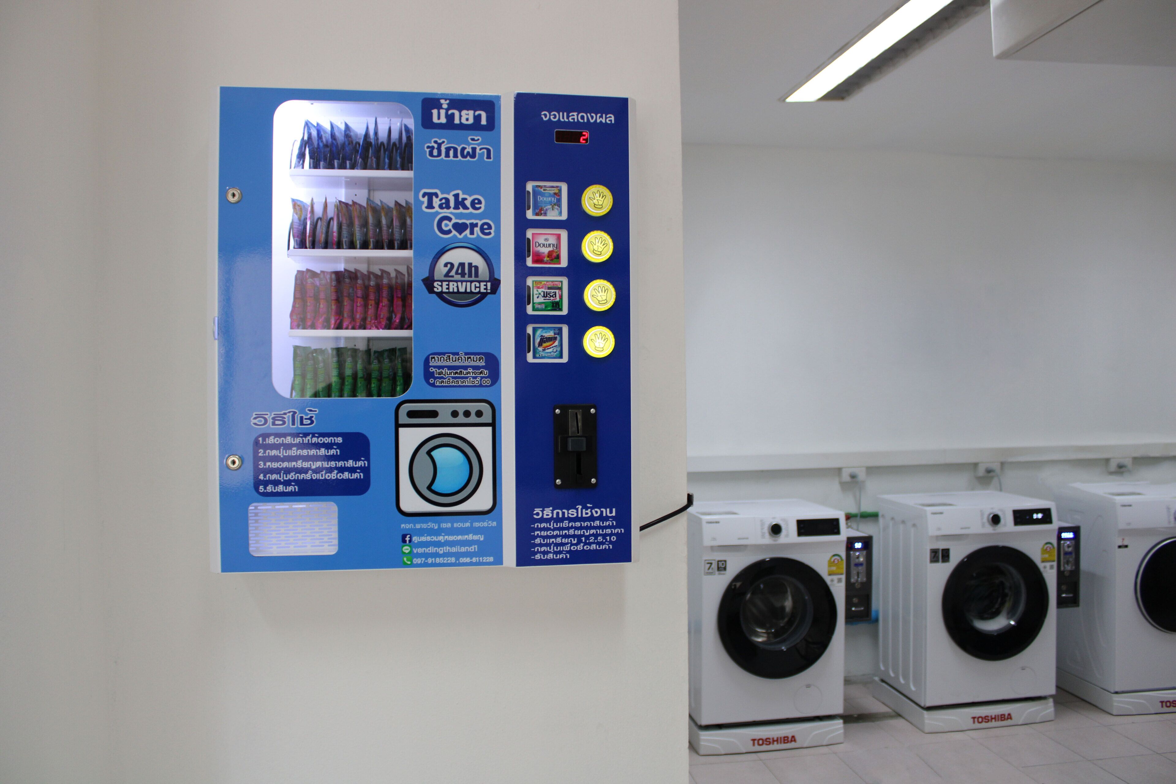 A laundry facility with multiple washing machines and a service sign.