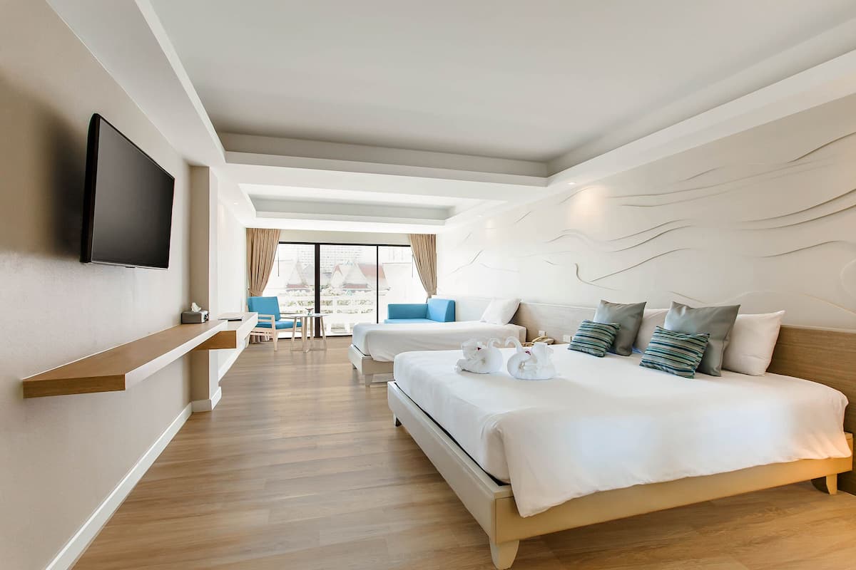 Hotelkamer met een groot bed, een aan de muur bevestigde televisie, een bureau en uitzicht op de stad door grote ramen.