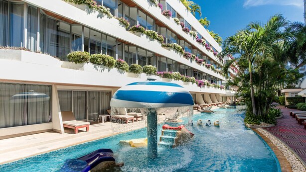 A hotel pool area with a water slide, lounge chairs, and a large umbrella. - The Cha-am Methavalai Hotel (Cha-am)