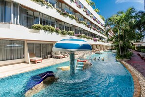 Zona de piscina de hotel con tobogán de agua, sillas de descanso y una sombrilla grande.