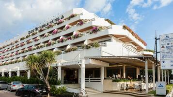 Um hotel com várias varandas decoradas com flores, entrada coberta e placa indicando os serviços.
