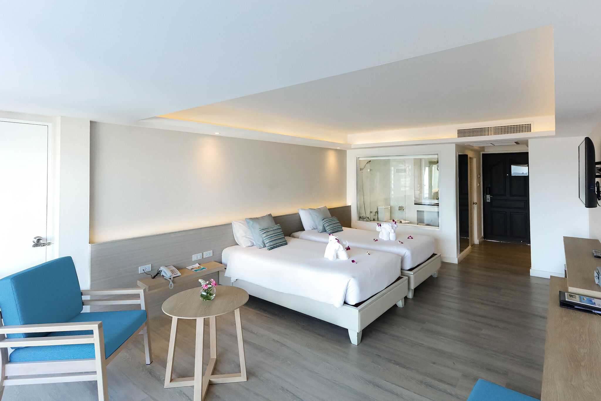 Une chambre d’hôtel avec deux lits, un bureau, une chaise et une petite table.