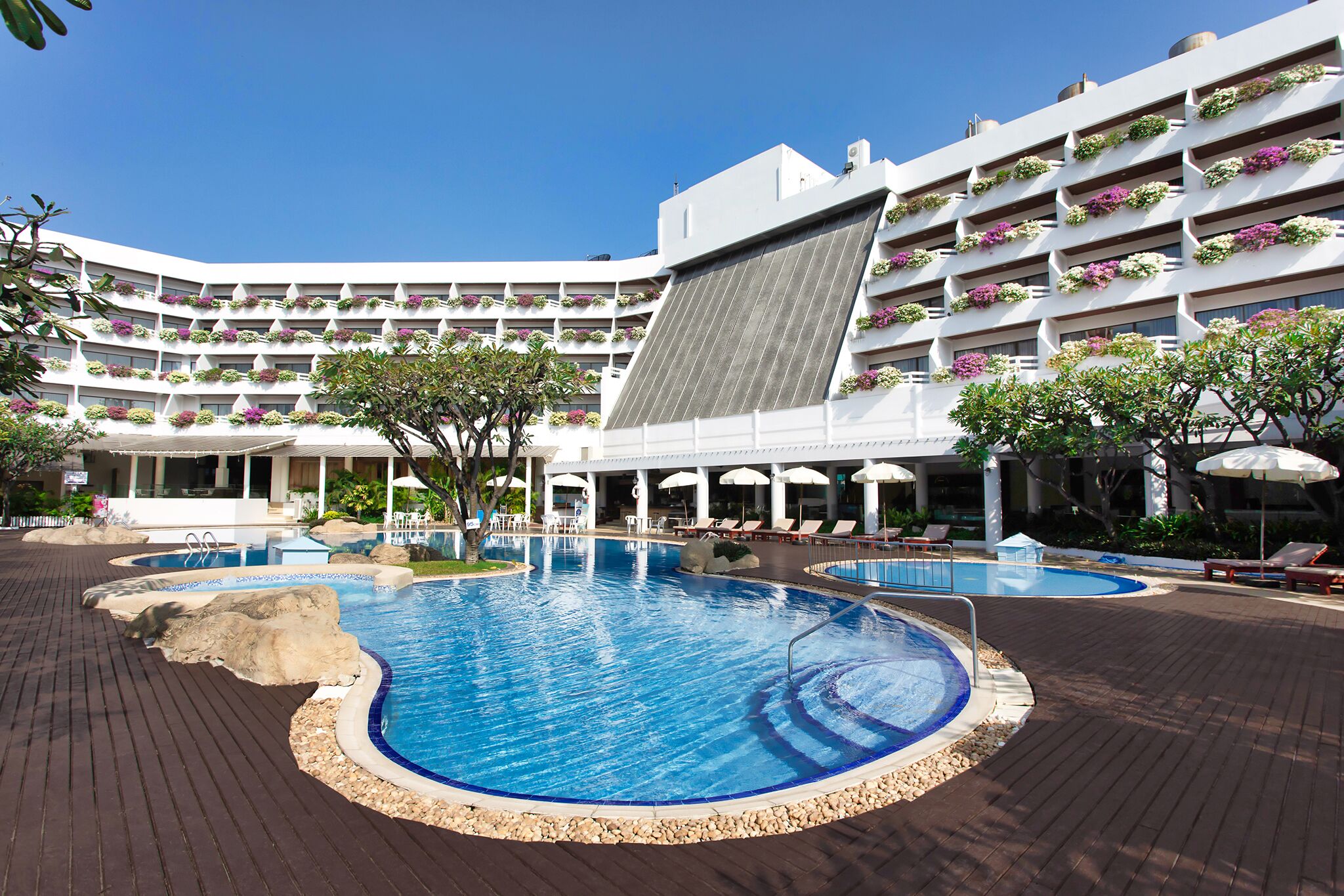 Un hotel con varias piscinas, zonas de estar al aire libre y un tobogán acuático grande.