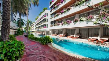 Un hotel con piscina, mobiliario exterior y balcones adornados con flores.