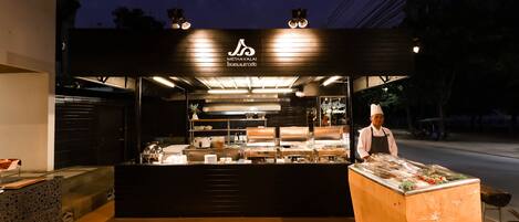 A restaurant with a modern design, featuring a black exterior and illuminated signage.