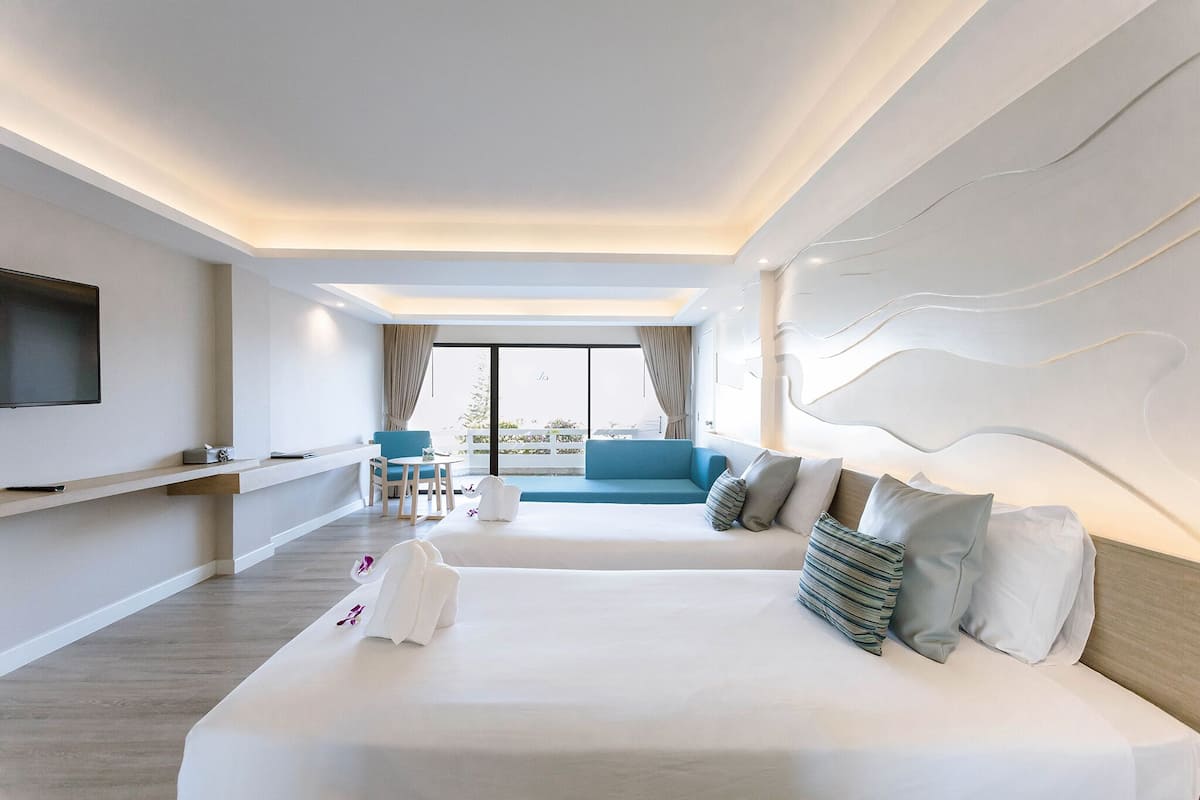 Een moderne hotelkamer met een groot bed, een bank, een televisie en een balkon met uitzicht.