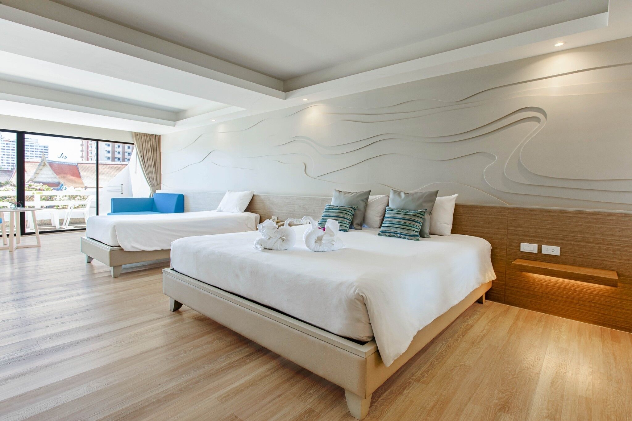Una habitación de hotel moderna con dos camas, un balcón y vistas a la ciudad.