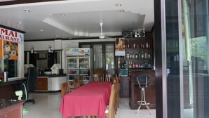 A restaurant interior with a dining area, a bar, and a counter with a menu. - Lamai Apartment (Patong)