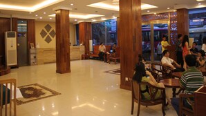 A spacious lobby with wooden pillars, a reception desk, and a seating area with tables and chairs. - Diamond Hotel (Phnom Penh)