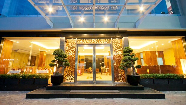 A hotel entrance with a glass canopy, decorative ironwork, and potted plants. - Diamond Hotel (Phnom Penh)