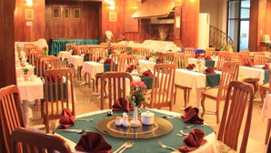 A large dining hall with multiple tables set for service, wooden chairs, and a central decorative arrangement. - Diamond Hotel (Phnom Penh)