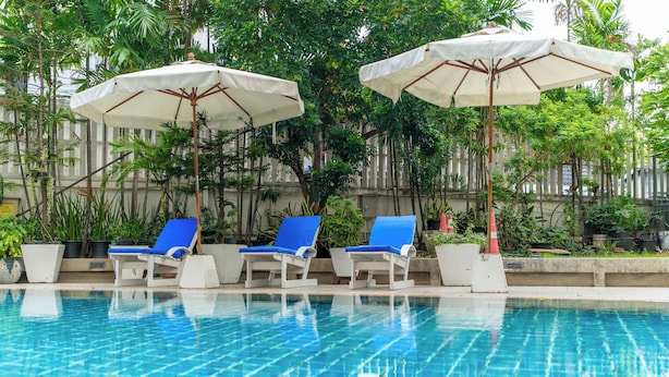 A swimming pool with blue lounge chairs and white umbrellas.