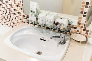 A bathroom sink with a glass shelf holding toiletries and a mirror above it. - Summit Pavilion (Bangkok)