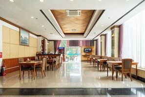 A spacious hotel lobby with a polished floor, wooden tables and chairs, a reception desk, and large windows with curtains. - Summit Pavilion (Bangkok)