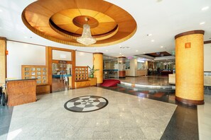 A lobby with a wooden reception desk, a chandelier, and a patterned floor. - Summit Pavilion (Bangkok)