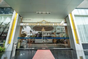 The entrance to the Summit Pavilion Hotel with a glass facade and a red carpet leading to the entrance. - Summit Pavilion (Bangkok)