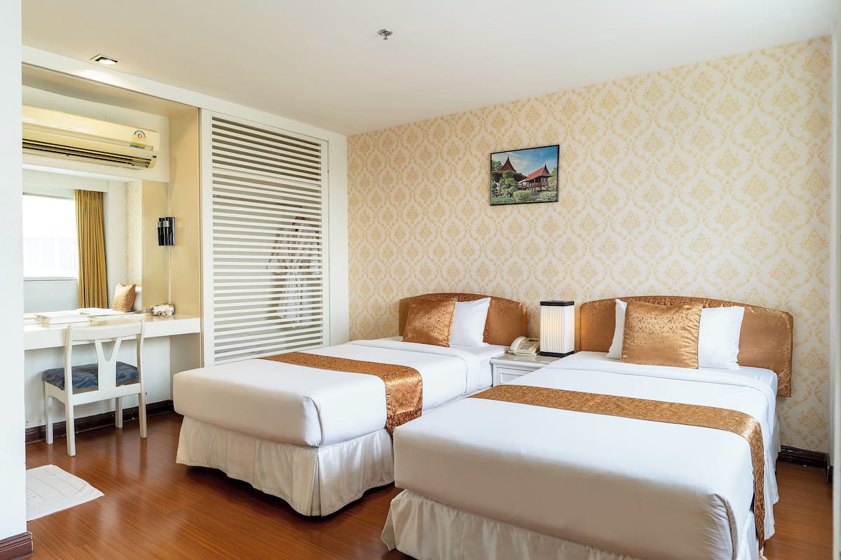 Habitación de hotel con dos camas, un escritorio y una ventana con persianas.