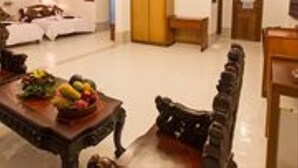 A hotel room with a bed, a wooden wardrobe, a dining table with fruit, and a sofa. - Asia Hotel (Phnom Penh)