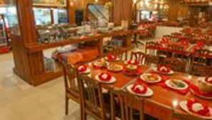 A restaurant with wooden interiors, multiple dining tables, and chairs. - Asia Hotel (Phnom Penh)