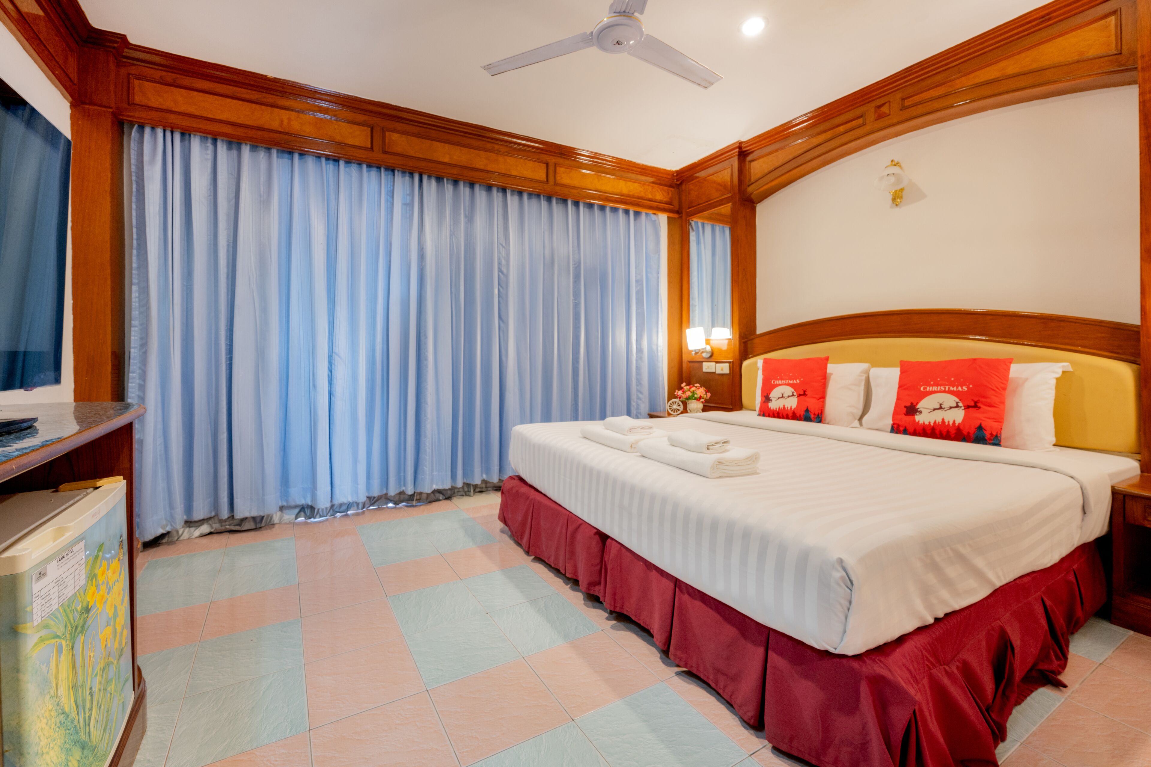 A hotel room with a large bed, wooden headboard, and a ceiling fan.