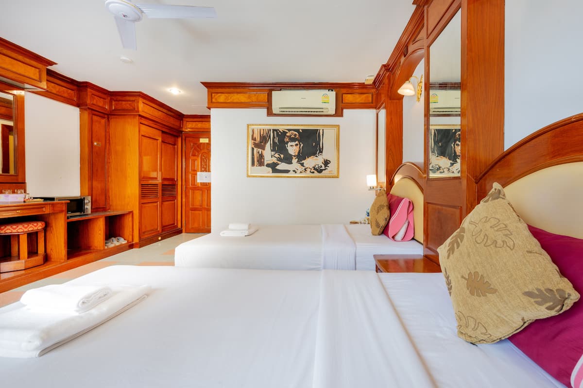 A hotel room with two beds, a desk, and a mirror.