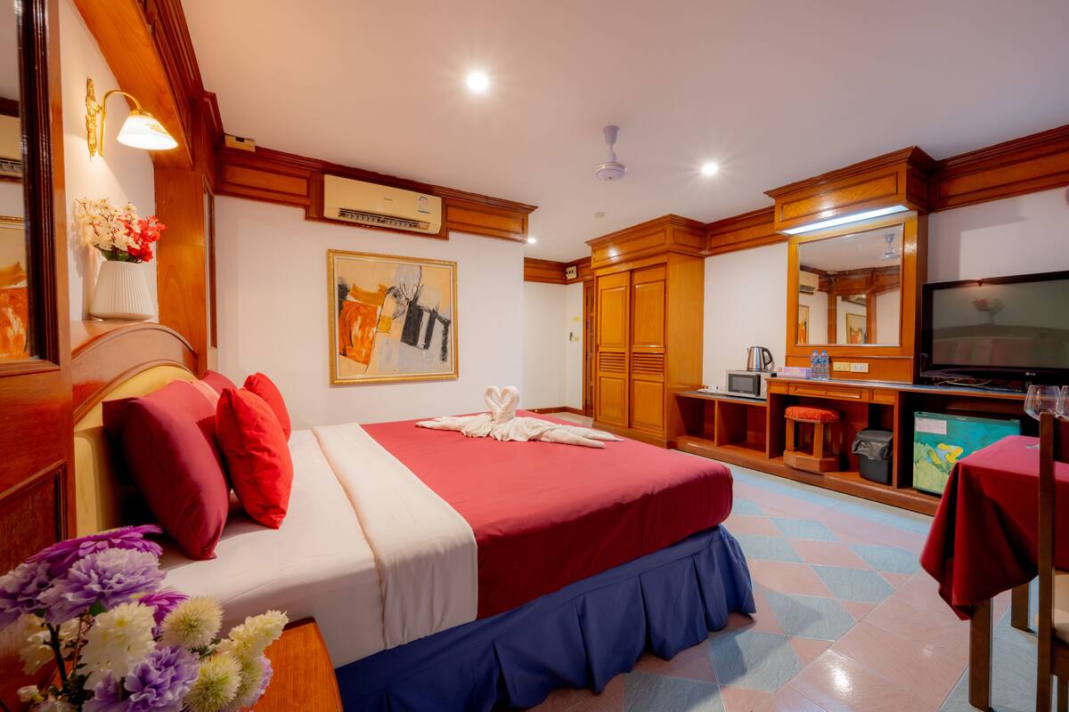 A hotel room with a bed, a desk, a television, and a bathroom.