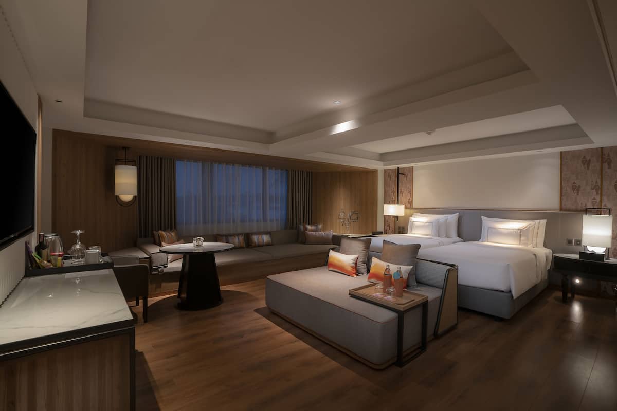 Ein modernes Hotelzimmer mit einem großen Bett, einer Couch, einem Esstisch und einem Fernseher.
