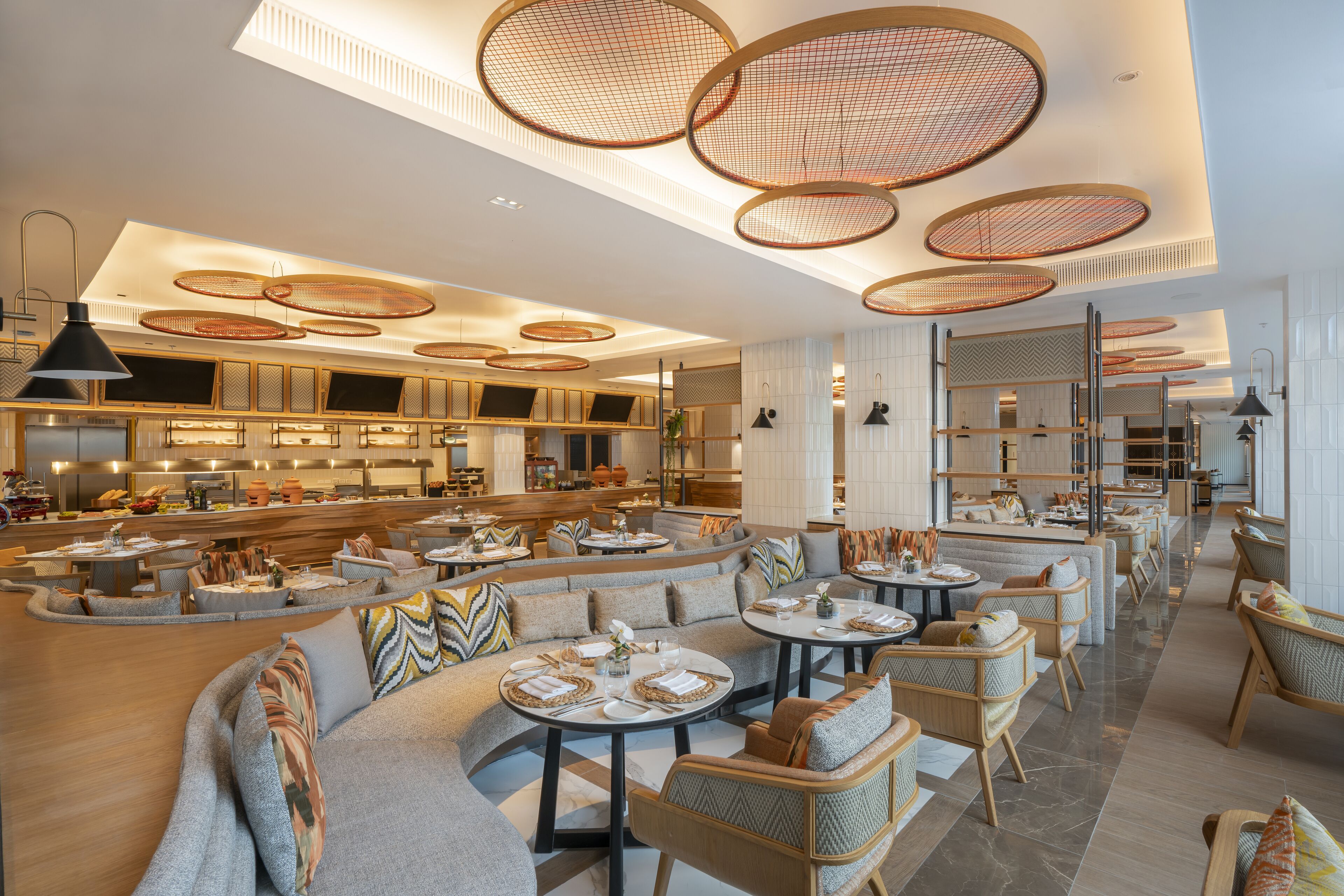 A modern hotel lobby with round tables, comfortable seating, and a central bar area.