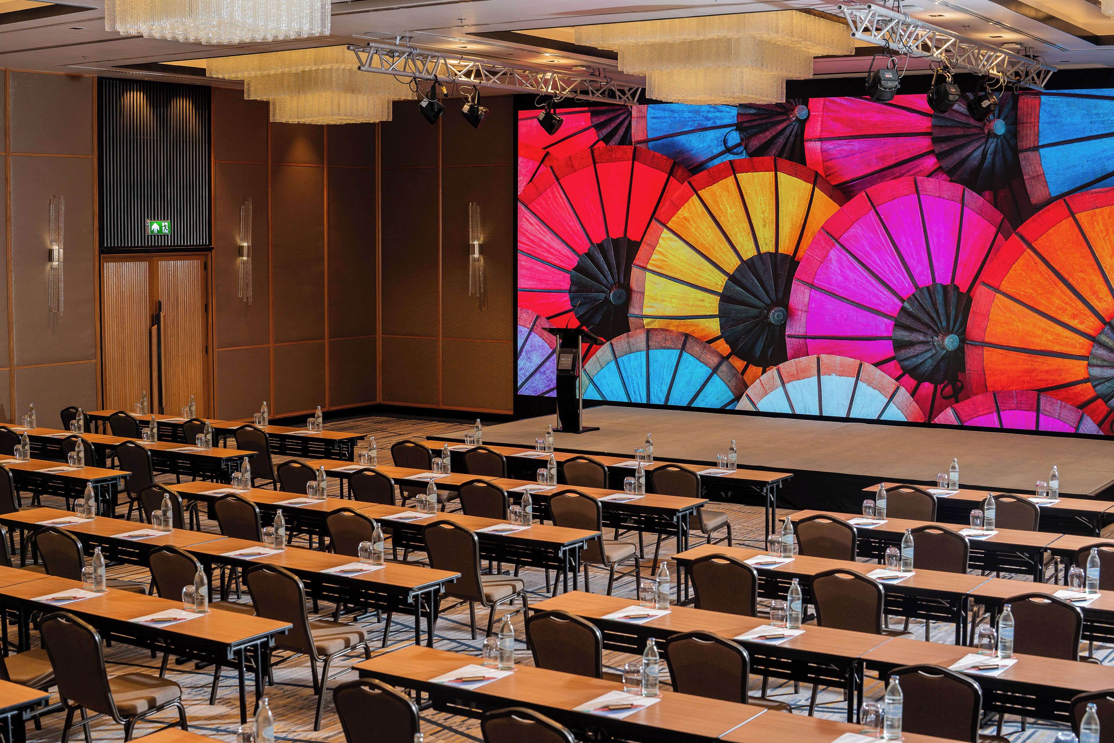 A conference room with rows of tables, chairs, and a large screen displaying colorful umbrellas.