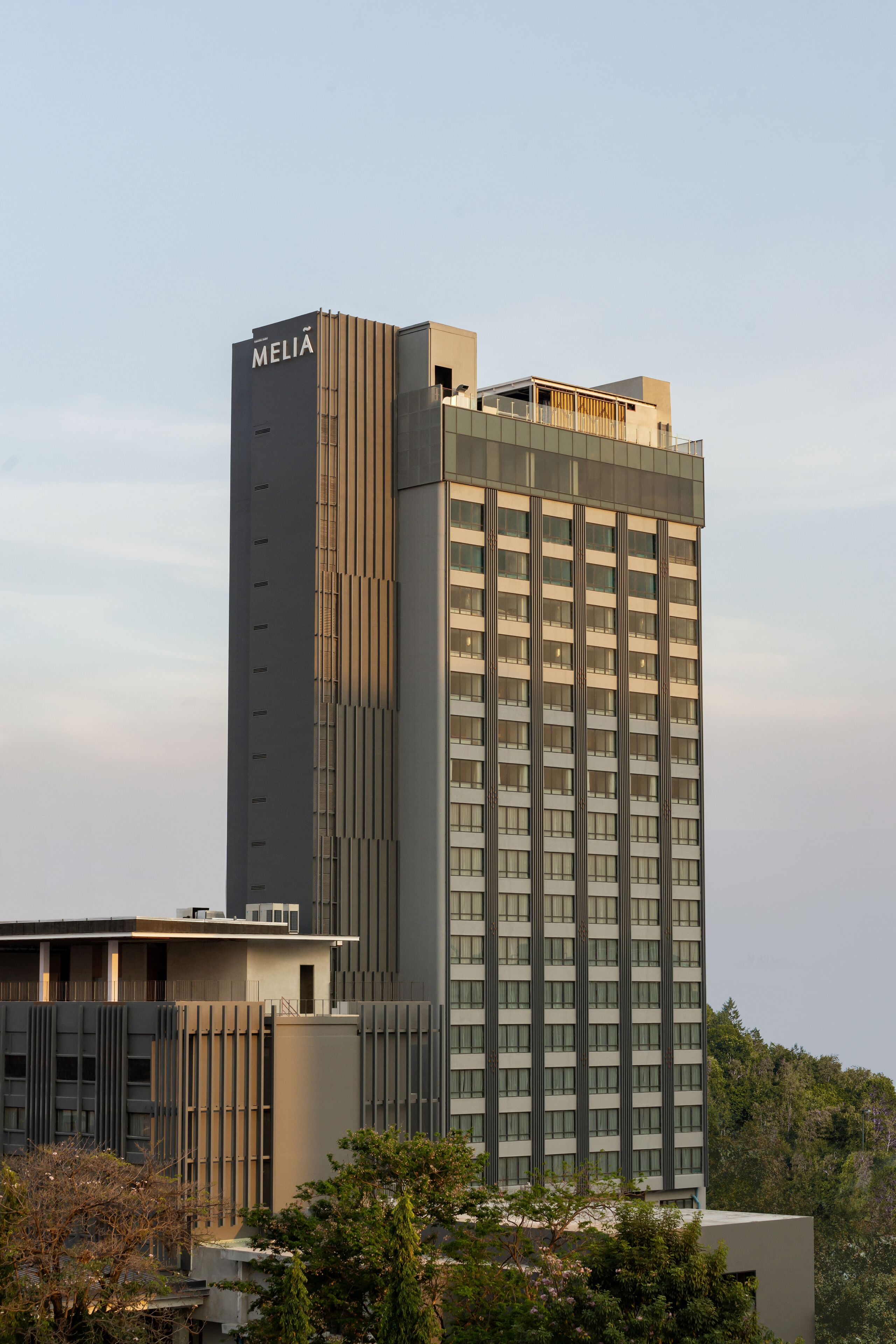 Un grand hôtel moderne, avec une enseigne  « MELIA » bien visible sur le toit. Il se caractérise par une façade composée d’une grille de fenêtres et un toit plat.