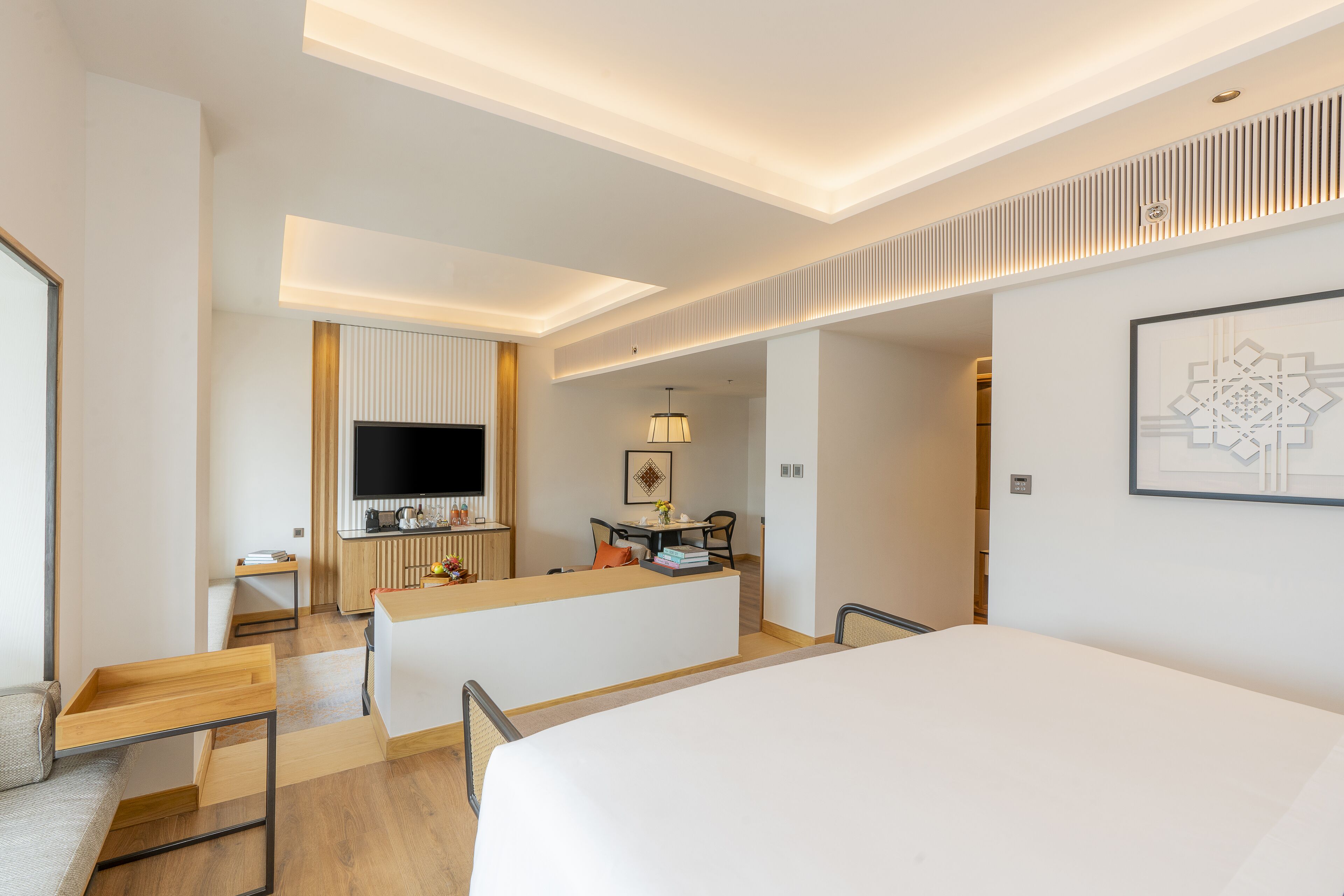 Una habitación de hotel moderna con una cama grande, un escritorio, un televisor de pantalla plana y un comedor.