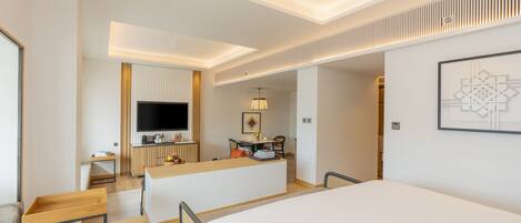 Una habitación de hotel moderna con una cama grande, un escritorio, un televisor de pantalla plana y un comedor.