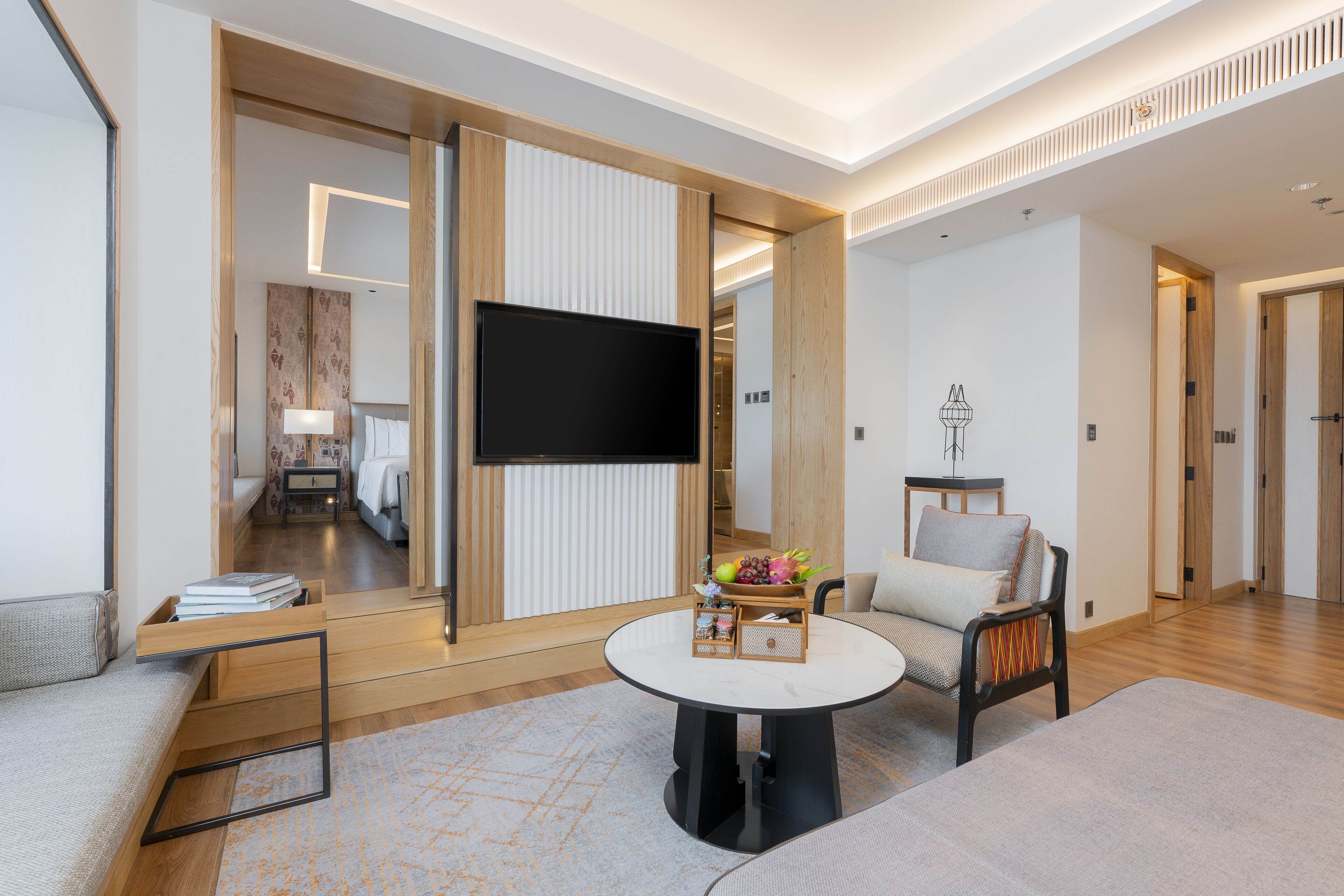 A modern living room with a flat-screen TV, a round coffee table, and a sofa.