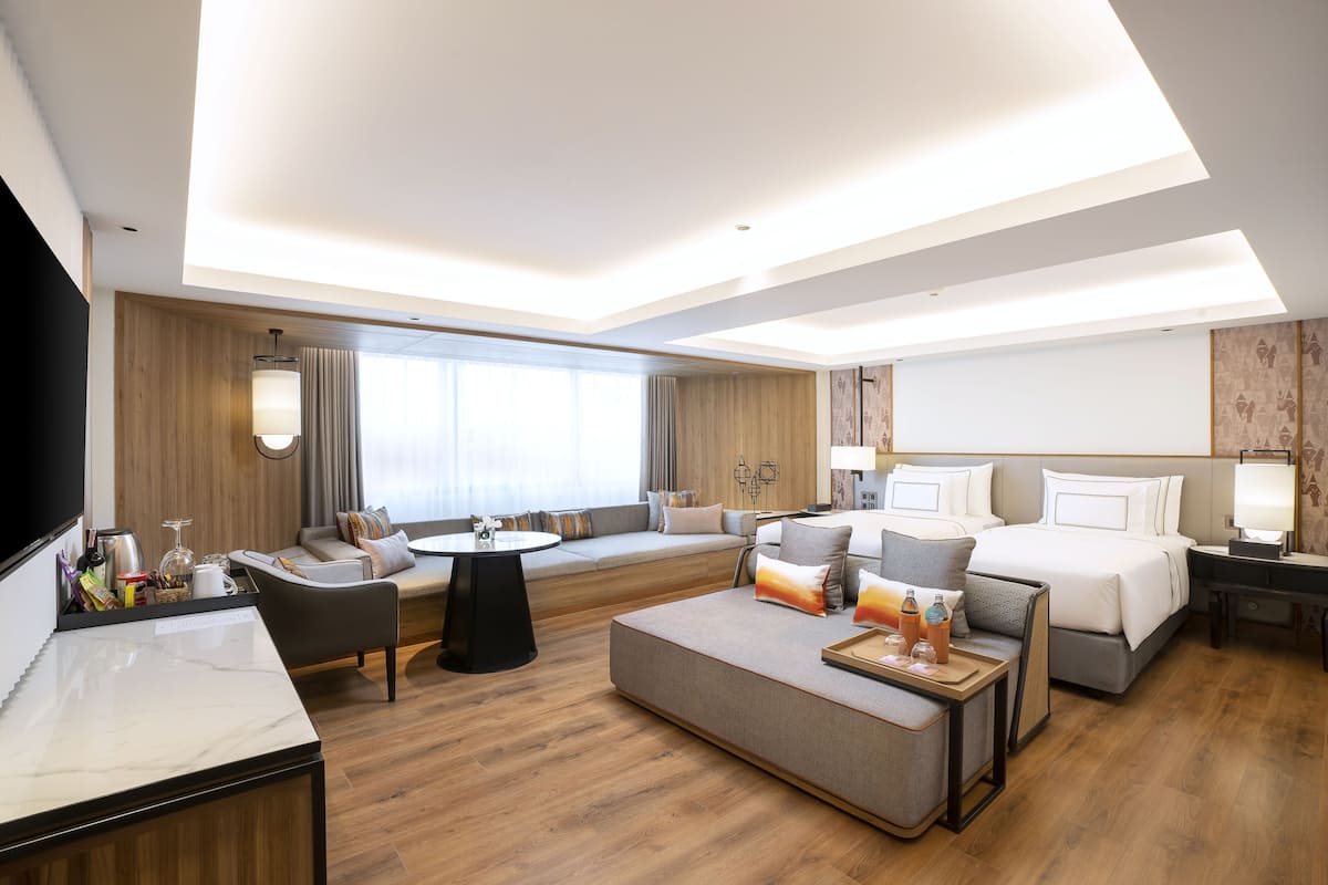 Ein modernes Hotelzimmer mit einer Couch, einem Bett, einem Esstisch und einem Fernseher.