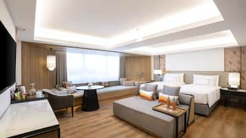 Una habitación de hotel moderna con sofá, cama, mesa de comedor y televisor.