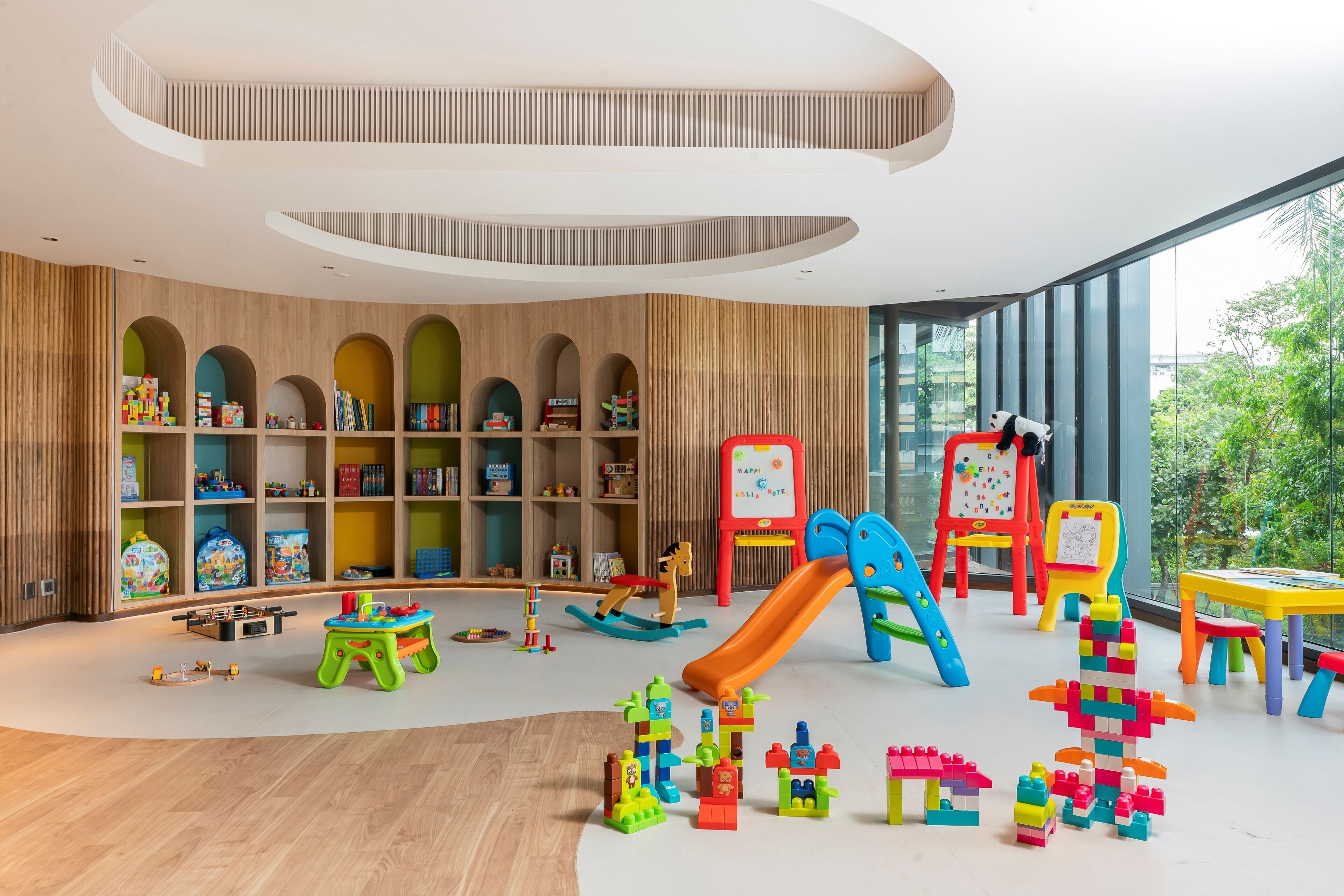 A modern children's play area with wooden shelving, colorful toys, and a slide.