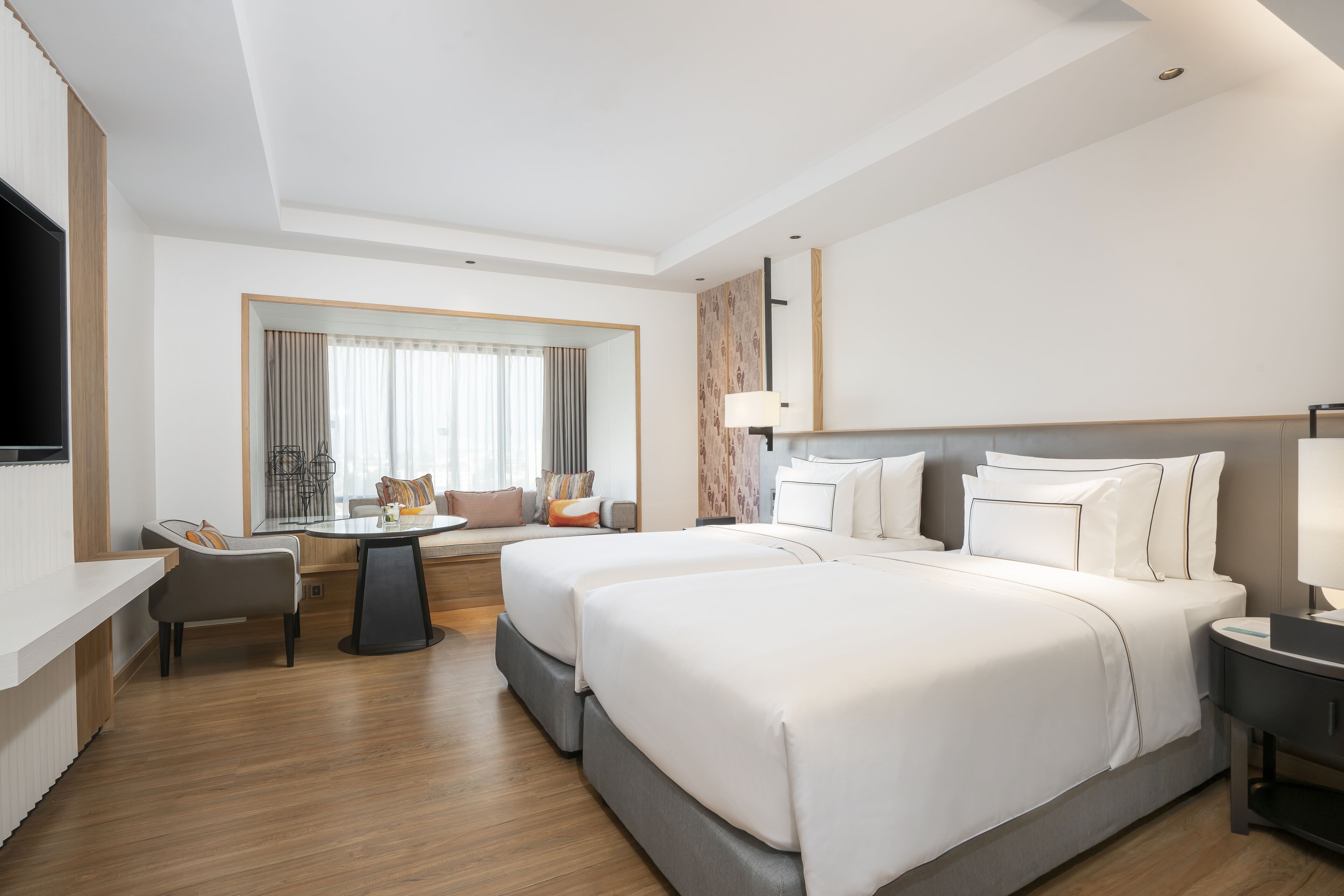 A modern hotel room with a large bed, a desk, and a television.