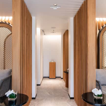 A hallway with a sofa and a table, wooden partitions, and a small table with a vase.