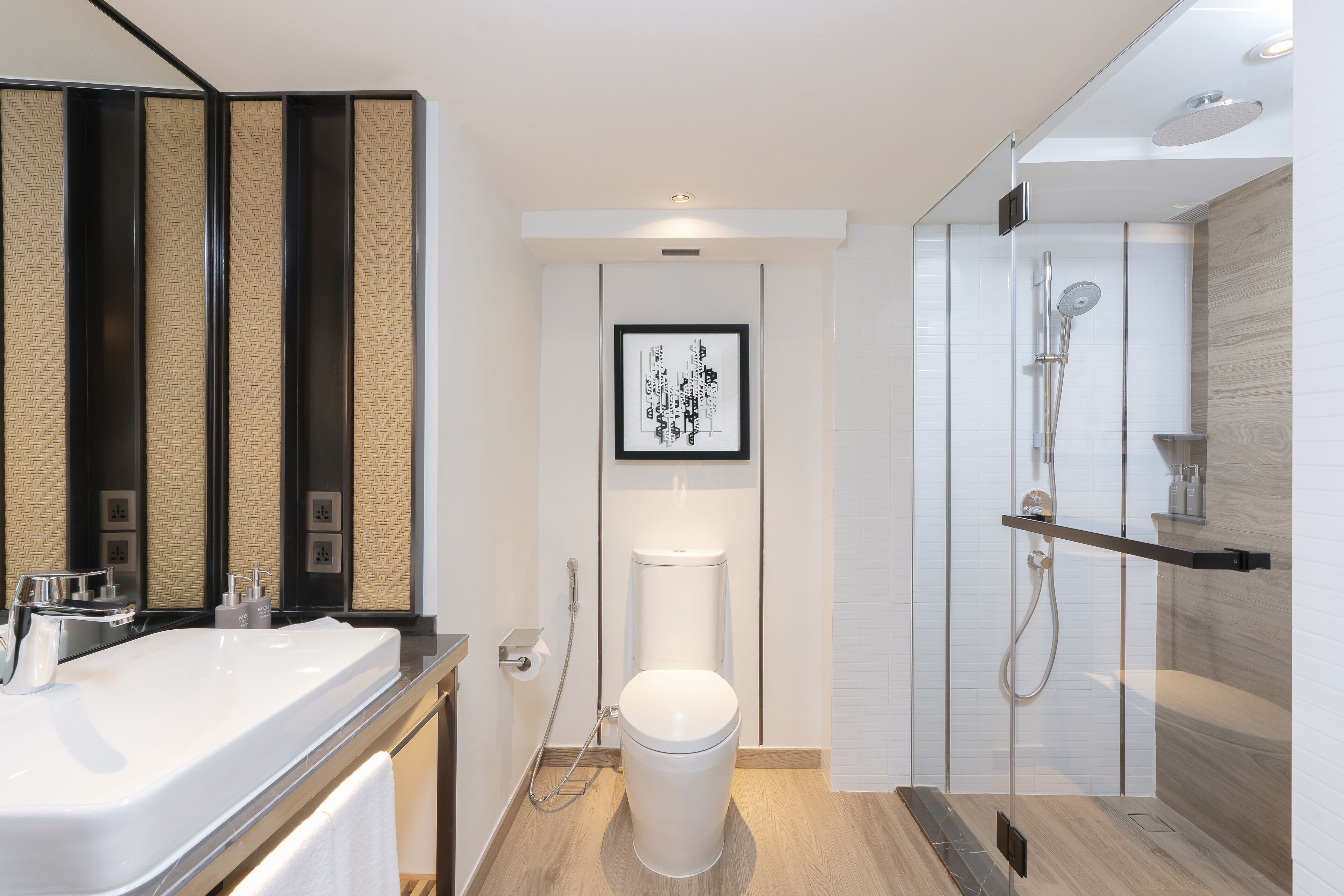A modern bathroom with a white sink, a toilet, and a glass-enclosed shower.