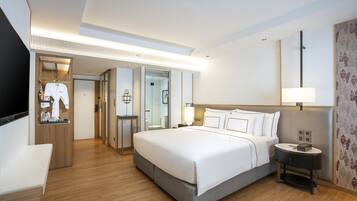 A hotel room with a large bed, bedside table, and a wardrobe.