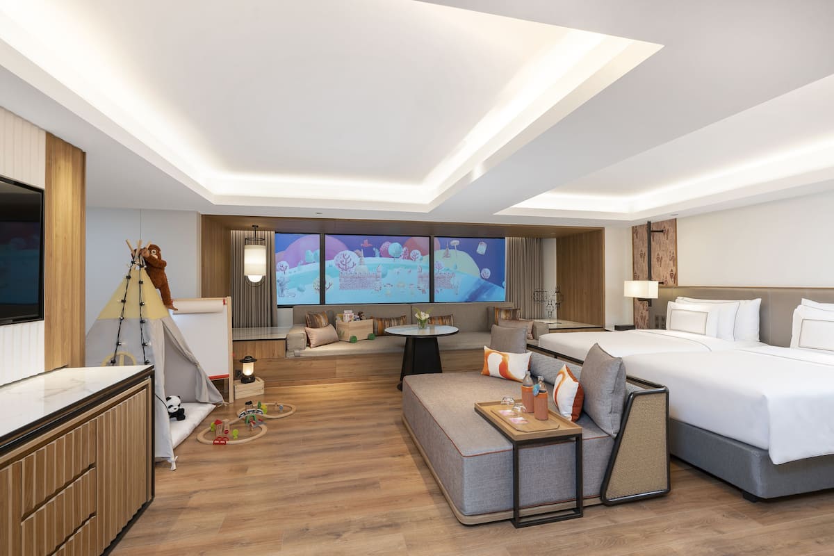 Ein modernes Hotelzimmer mit einem großen Bett, einer Couch, einem Schreibtisch und einem Fernseher.