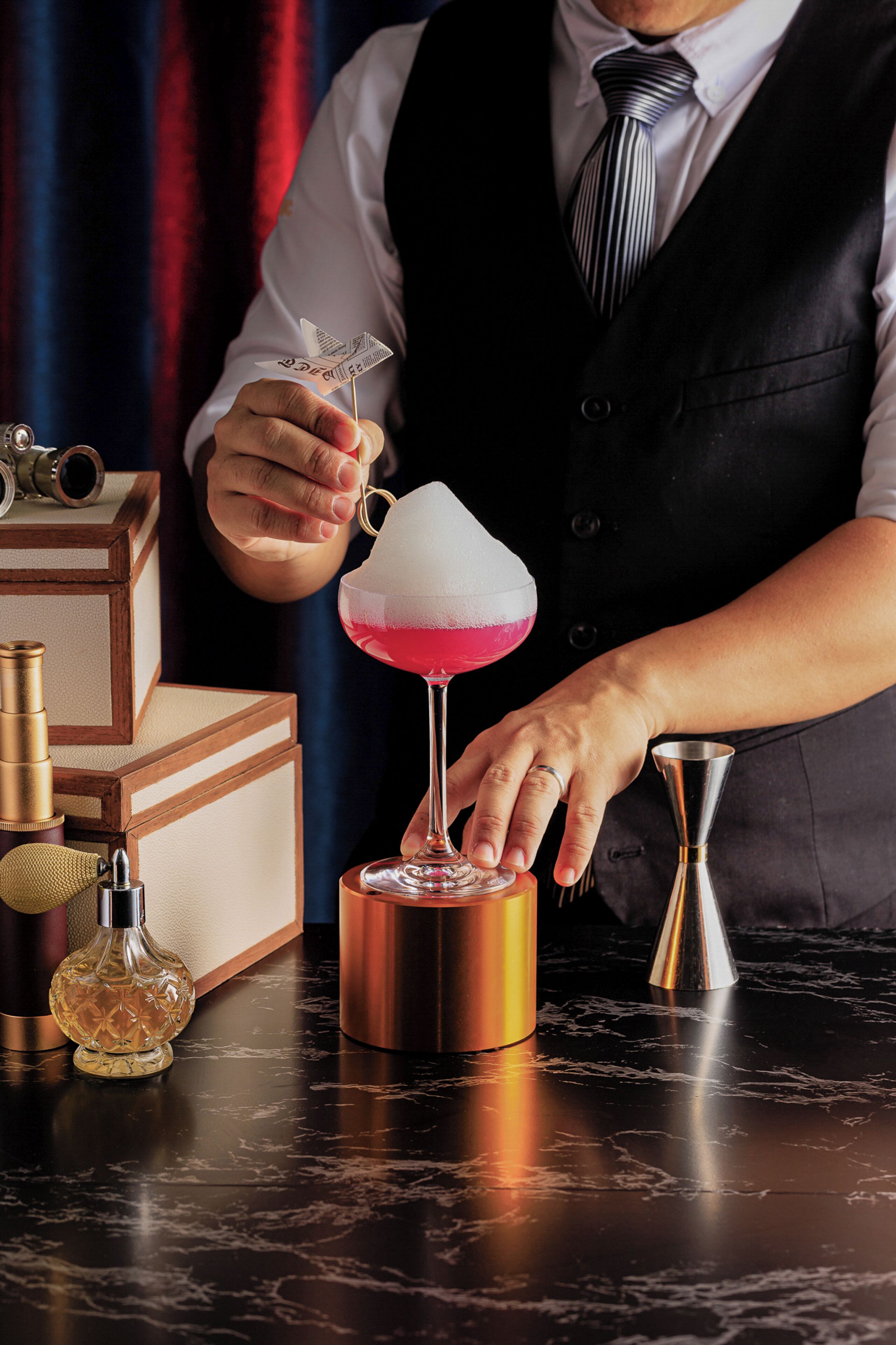 A bartender preparing a cocktail with a shaker and a glass.